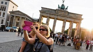 <p>Zwei Touristinnen fotografieren sich vor dem Brandeburger Tor in Berlin.</p>