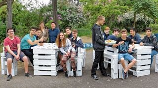 <p>Unterricht im Grünen: Um den stickigen Klassenzimmern zu entkommen, haben Schüler der Gesamtschule Oggersheim Möbel selbst gebaut und im Pausenhof aufgestellt. Lehrerin Ribana Weickenmeier (links, hinter dem Tisch) ist stolz.</p>