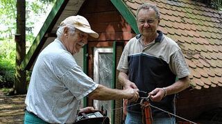 <p>Ob das die Füchse abschreckt? Vereinsmitglied Ulrich Lehn (l.) prüft, ob Strom auf dem vom Vorsitzenden Reinhard Menger aufgestellten Zaun fließt.</p>