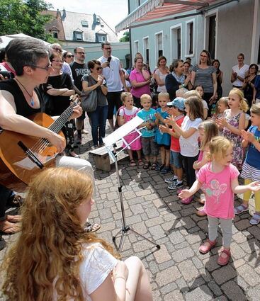 <p>Die Kindergartenkinder eröffneten das Gemeindefest mit Gitarrenbegleitung von Conny Willhauck (Erzieherin Arche Noah, l), im Hof gab es Kinderschminken, r. unten das MEF-Team, v.l.: Christine Bruckmeir, Stephanie Uhlen und Sandra Taut.</p>
