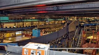 <p>Pakete sausen auf einem 9,5 Kilometer langen Netz aus Transportförderbändern durch das Speyerer DHL-Zentrum. Ein Scanner (unten) liest die Adressdaten.</p>