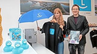 <p>Schirme und T-Shirts mit dem Ludwigshafen-Logo präsentieren Julia Gräf und Ralph Beetz in der vergrößerten Tourist-Information am Berliner Platz.</p>