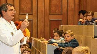 <p>Frühgeborene bekommen ihre Nahrung über eine Spritze in die Magensonde: Thomas Schaible, Direktor der Klinik für Neonatologie, erläutert was zu tun ist, wenn ein Kind nach der Geburt im Brutkasten (Inkubator) aufwachsen muss.</p>