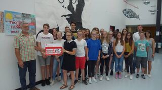 <p>Die Schülerin Pascale Kratzer bei der Übergabe des Spendenschecks an Bernhard Finkbeiner vom Verein Focus. Rechts im Hintergrund Klassenlehrerin Anna Bieg und Schulleiter Jascha Detig.</p>