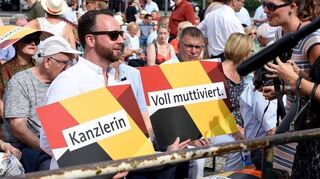 <p>"Voll muttiviert", "Kanzlerin" und "Angela Merkel" steht auf den Plakaten, die im Publikum in die Höhe gehalten werden.</p>