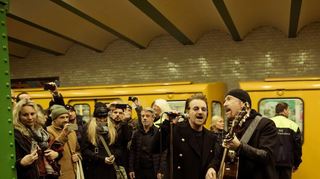 Bono (Mitte) und Gitarrist The Edge bei einem U2-Überraschungskonzert am Mittwochabend in einer Berliner U-Bahn-Station.
