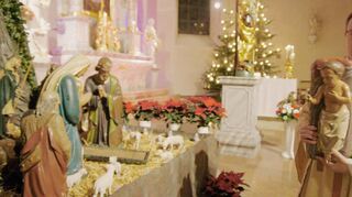 Pfarrvikar Virginijus Grigutis trägt zu Beginn der Christmette in St. Andreas den Messias zur Krippe.