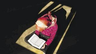 Eine junge Muslimin liest im Koran. Nur wenige Verse darin drehen sich um die Kleidung der Frau – dennoch wird die Schrift herangezogen, um das islamische Kopftuchgebot zu legitimieren.