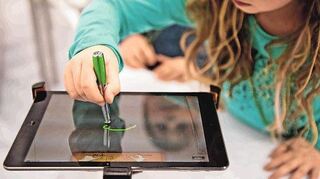 Ein Mädchen spielt an einem iPad. In den ersten Lebensjahren sollte Kinder aber vor allem in der realen Welt unterwegs sein.