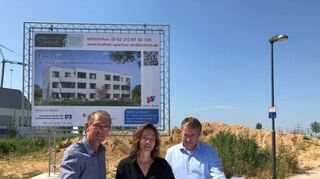 Bürgermeister Michael Kessler (v.l.), Projektleiterin Adriane Gunzer und Pilgerhaus-Vorstand Uwe Gerberich-Demmer mit Plänen vor dem Bauplatz.