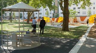 Der Spielplatz mit gelben Verkleidungen und überdachtem Karussell.