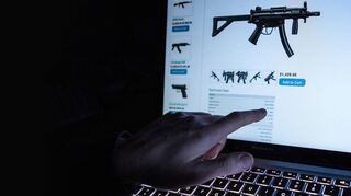 Handel im Verborgenen: Ein Mann zeigt auf unserem Illustrationsbild auf die Internetseite eines Online-Shops im Darknet, der Maschinenpistolen verkauft.