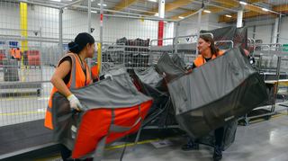 Gladys Perugachi (li.) aus Fürth im Odenwald und die Mannheimerin Nina Hagen beladen einen Rollwagen mit Paketen im Amazon-Verteilzentrum.