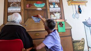Ein Patient und Beate Tanzer, Betreuungskraft, sitzen vor einer sogenannten Memory-Station im Krankenhaus Gesundbrunnen.