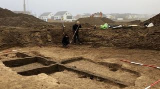 Die Spuren zweier Grubenhäuser haben Archäologen hier freigelegt. Im Hintergrund Häuser des ersten Abschnittes im Neubaugebiet „Mitten im Feld“.