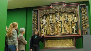 Irmgard Siede (Mitte), Kuratorin der neuen Ausstellung „Glaubensschätze“, erklärt Besuchern den „Rother Altar“.