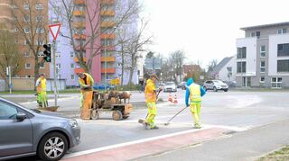 Die alten Markierungen an der Kreuzung werden entfernt während der Verkehr daran vorbeifließt – oder kurz warten muss.