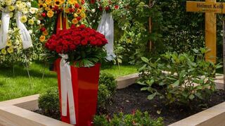 Das Kreuz aus Holz, die Umrandung aus dekorativem Stein: das mit bunten Blumen und Kränzen geschmückte Grab von Altkanzler Helmut Kohl am Sonntag.