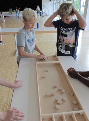 Der neunjährige Emil und der zehnjährige Elias sammeln Punkte am Shuffleboard, während Tamara Reuter vom TV Hofheim mit den Mädchen „Inselhüpfen“ spielt.