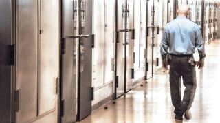 Ein Justizbediensteter geht an geschlossenen Zellentüren in der Justizvollzugsanstalt in Frankfurt vorbei.