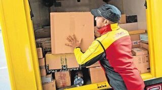 Ein Paketbote stellt in Düsseldorf ein Paket in ein Fahrzeug der Deutschen Post DHL. Zwölf Millionen Sendungen sind in Deutschland jeden Tag unterwegs zu ihren Empfängern.