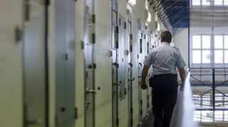 Ein Vollzugsbeamter geht während eines Kontrollgangs in der Justizvollzugsanstalt in Bruchsal an den Zellentüren der Insassen vorbei.