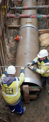 Mitarbeiter des Eigenbetriebs Stadtentwässerung Mannheim verlegen mit Hilfe eines Baggers das neue Teil eines Abwasserkanals in die Erde.
