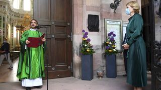 Dekan Karl Jung und Bundesministerin Julia Klöckner vor der verhüllten Plakette bei der Gedenktafelenthüllung für Helmut Kohl an der Jesuitenkirche.