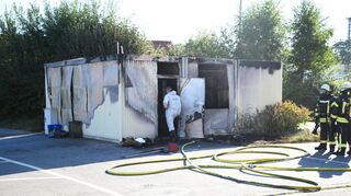 Einsatzkräfte von Polizei und Feuerwehr ermitteln bei dem Containerbrand in Meckesheim.