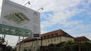 Neu und Alt auf Hammonds: Links Baustellenschild mit Projektion des neuen Quartiers, rechts die historischen Kasernengebäude, die erhalten bleiben.