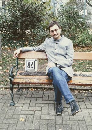 Auf einer Bank in Wien: Fabian Burstein mit Buga-Logo.