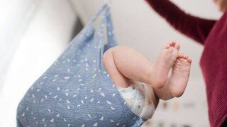 Eine Hebamme wiegt im Rahmen der Nachsorge ein Baby.
