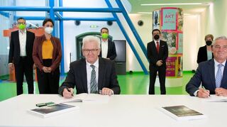Ministerpräsident Kretschmann (l.) und CDU-Landeschef Thomas Strobl unterzeichnen den Koalitionsvertrag. Im Hintergrund: Spitzenpersonal der Parteien.