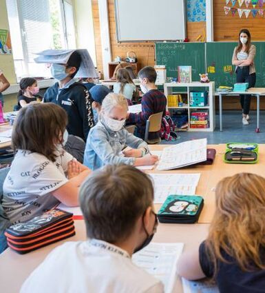 Schulkinder sitzen mit Maske im Unterricht.