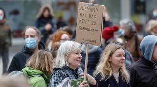 Eine Frau hält auf einer Demonstration von Corona-Leugnern und Kritikern der staatlichen Maßnahmen zur Eindämmung der Corona-Pandemie ein Schild.
