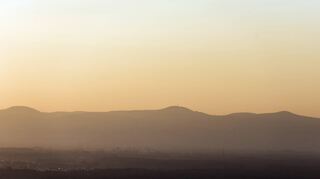 Die Rheinebene heizt sich auf: Blick auf die im Sonnenuntergang rötlich leuchtende Hügelkette der Haardt mit der Kalmit bei Neustadt als höchster Erhebung.