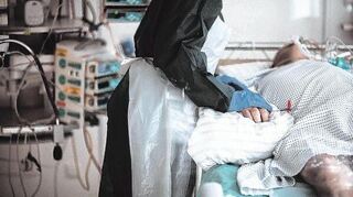 Eine Mitarbeiterin der Pflege in Schutzausrüstung betreut einen Covid-Patienten. In der Corona-Krise mussten Pflegekräfte auf Intensivstationen noch mehr Personen betreuen als üblich.