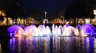 Die Wasserfontänen am Wasserturm in Mannheim erstrahlen in Regenbogenfarben.