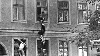 1961: Eine 77-jährige Frau will in die Freiheit springen. DDR-Uniformierte halten sie an den Armen fest, West-Berliner ziehen an den Beinen.