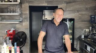 Claus Eisenmann hinter dem Kiosk-Tresen auf seiner Minigolfanlage in Viernheim. Das verschmitzte Lächeln könnte sein Markenzeichen sein.