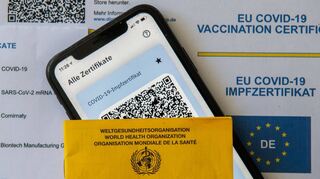 Ein Impfpass und ein Smartphone, auf dem die App CovPass läuft, liegen auf einem Impfzertifikat, das von einer Apotheke ausgestellt wurde. Der digitale Nachweis ist eine freiwillige Ergänzung des weiter gültigen gelben Impfheftes aus Papier. Kriminelle wittern allerdings ein Geschäft mit gefälschten Impfdokumenten.