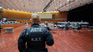 Ein Justizbeamter steht zu Beginn des VW-Prozesses in der Stadthalle Braunschweig. Hier tagt das Landgericht, damit alle Beteiligten Platz haben.