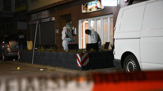 Ermittler arbeiten auf dem Mannheimer Waldhof hinter einem Polizeiabsperrband. Zuvor waren dort mehrere Schüsse gefallen.