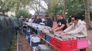 Plattenflohmarkt in der Uhlandschule: mehrere Sammler beim sogenannten Diggen, also dem Wühlen und Stöbern in aufgestellten Plattenkisten.