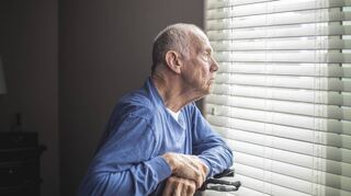 Ein betagter Mann schaut aus dem Fenster seines Krankenhauszimmers.