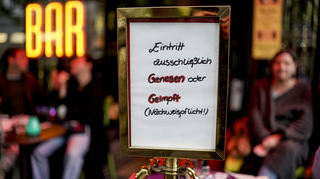 Vor einer Bar steht ein Hinweisschild, welches auf den Einlass nach der 2G-Regel hinweist.