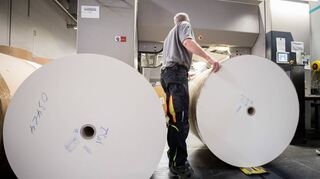 Ein Mann wechselt Papierrollen für den Buchdruck bei einer Druckerei in Schleswig-Holstein.