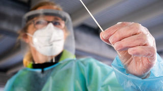 Eine Helferin hält einen Coronavirus-Teststab.