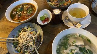 Reich gedeckter Tisch mit der Nationalspeise Pho, einer Hühnersuppe (rechts unten).