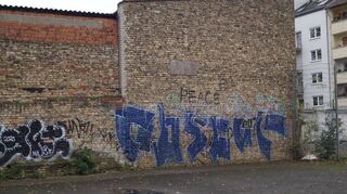 “Rescue in peace“ (Ruhe in Frieden) steht auf der Wand am Kickplatz, dessen Bodenbelag, in die Jahre gekommen ist und Verletzungsgefahr birgt.